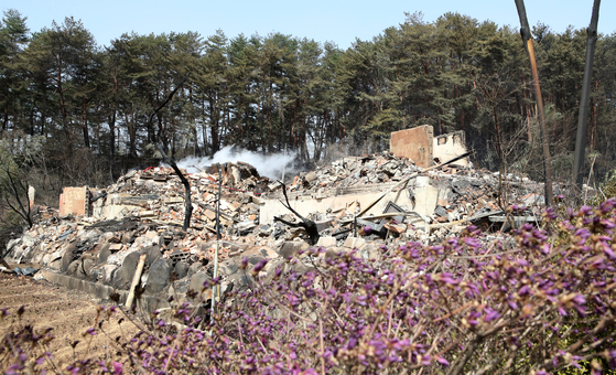 Smoke goes up over remnants of a burnt-down building in Gangneung, Gangwon, on Wednesday, after a massive forest fire broken out in the previous day. [YONHAP]