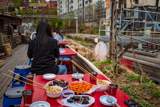 Cheolgil Tteokbokki's outdoor tables overlook the view of trains passing on the railroad. [BAEK JONG-HYUN]
