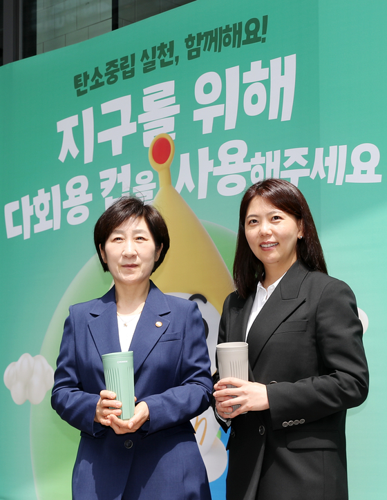 Environment Minister Han Wha-jin, left, and McDonald's Korea CEO Kim Ki-won pose for a photo after purchasing coffee in tumblers at the McDonald's Coex chain in Gangnam District, southern Seoul, on Friday. [NEWS1]
