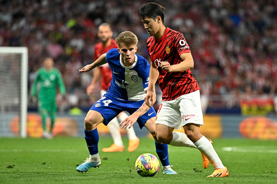 Lee Kang-in of Mallorca, right, fights for the ball with Atletico Madrid’s Pablo Barrios during a La Liga game in Madrid on Wednesday. Lee came on as a substitute in the game after leading Mallorca to a 3-1 win over the weekend and taking back-to-back man of the match honors.  [AFP/YONHAP]