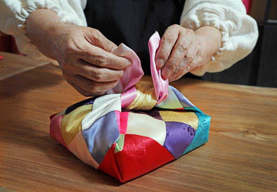 Lee showcases how to giftwrap using her bojagi. [PARK SANG-MOON]