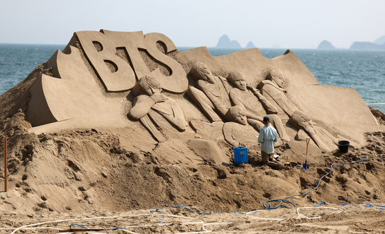 A foreign artist creates sand artwork of the K-pop boy band BTS at Haeundae Beach in Busan on Monday. The 2023 Haeundae Sand Festival, themed "Expo Sand Sea for the Future of 2030," will be held from Friday to Monday at Haeundae Beach and Gunam-ro Haeundae Square. [YONHAP]