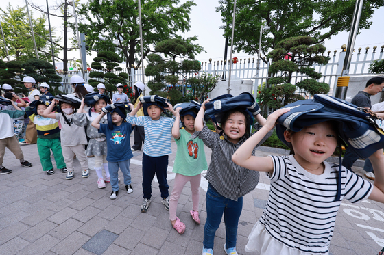Children take part in a nationwide civil air defense drill in front of the Seoul Metropolitan Government Complex in central Seoul Tuesday afternoon. The drill, requiring civilians to head to nearby evacuation facilities or safe locations to prepare for an emergency situation, such as a possible threat from North Korea, was resumed after a six-year suspension. [YONHAP]
