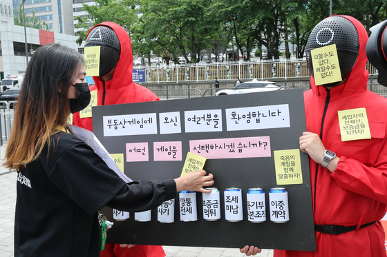 A group of rental fraud victims hold a satirical performance in front of the presidential office in Yongsan, central Seoul on Thursday. The eight cans attached to the board are labeled with loopholes in the property law that the group blames for the scam. [YONHAP]