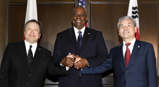From left, Japanese Defense Minister Yasukazu Hamada, U.S. Secretary of Defense Lloyd Austin and South Korean National Defense Minister Lee Jong-sup hold hands before trilateral talks on the sidelines of the annual Shangri-La Dialogue in Singapore on Saturday. [JOINT PRESS CORPS]