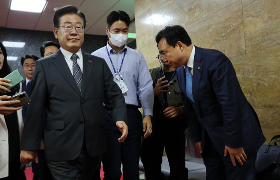 Rep. Youn Kwan-suk, right, bows to Democratic Party leader Lee Jae-myung as he passes in the National Assembly in Yeouido, western Seoul on Monday. [YONHAP]