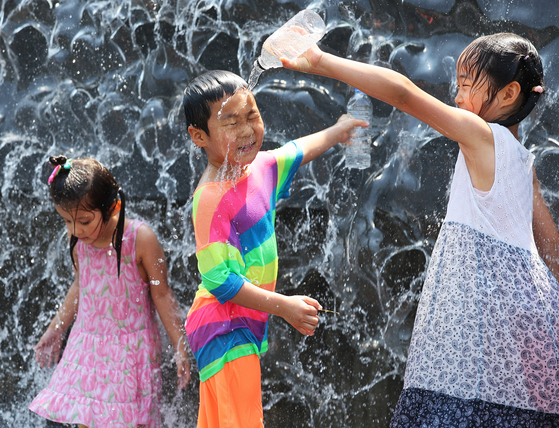 Children cool off at a water fountain at Gwanggyo Lake Park in Suwon on Sunday. With temperatures rising, some areas including Seoul issued their first heat wave advisories of the year during the weekend. Daegu, one of the hottest cities in the country, warned against outdoor activities on Saturday while Seoul issued the same warning on Sunday. [YONHAP] 