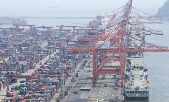 Cranes load containers for export on outbound ships at a port in Busan on June 12. [YONHAP]