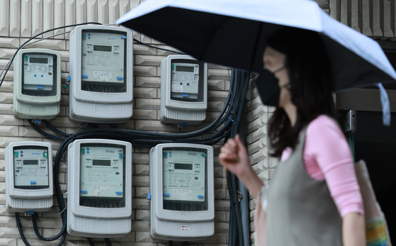 A pedestrian walks past electricity meters affixed to a wall in central Seoul. The Korea Electric Power Corporation on Wednesday announced its decision to freeze the electricity rate in the third quarter. [YONHAP]