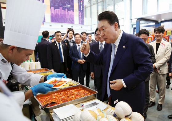 Korean President Yoon Suk Yeol, right, gives a thumbs up after tasting tteokbokki (spicy rice cakes) at a K-food booth at the Korea-Vietnam Partnership Fair at a convention center in Hanoi Thursday. [JOINT PRESS CORPS]