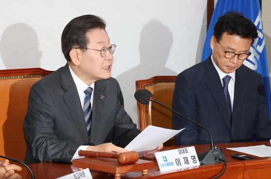 Democratic Party leader Lee Jae-myung, left, speaks at the party's supreme council meeting at the National Assembly in Yeouido, western Seoul, on Monday. [YONHAP]