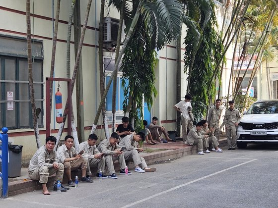 Students at VXT, an agency that helps people with overseas employment, take a rest on a street in Hanoi after class on June 18. [LEE YOUNG-KEUN]