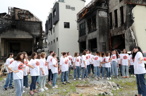 Ukrainian girls choir "Vognyk" perform in front of a hotel burned during a major wildfire that scorched a large swath of Gangneung, Gangwon in April. The group is participating in the World Choir Games that kicked off in Gangneung on Monday. [YONHAP]