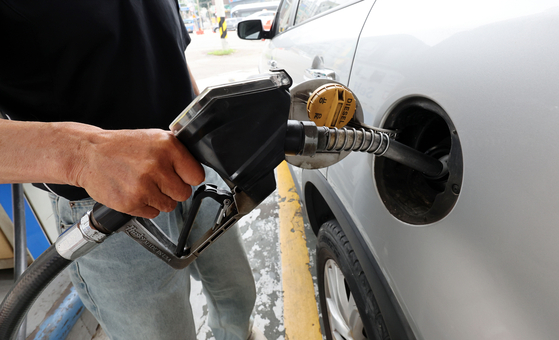 A customer pumps gas into a vehicle at a gas station in Seoul on Tuesday. Sharp drops in petroleum prices for the last two months helped ease inflationary pressure. [YONHAP] 