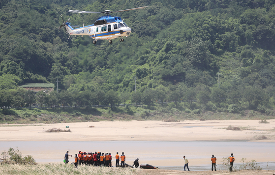A helicopter hovers over Naeseong Stream in Yecheon County, North Gyeongsang, on Wednesday in search of a marine who was swept away while looking for missing persons that morning. None of the marines in the search and rescue team were wearing life jackets at the time of the accident. The body of a man in his 70s was also found along the stream. Yecheon was hit hard by downpours last weekend, with landslides causing large numbers of deaths and evacuations.  [YONHAP]