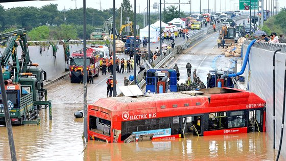 A rescue team on Sunday searches for bodies in the bus that was submerged in a flooded underpass in Osong-eup in Cheongju, North Chungcheong. [KIM SEONG-TAE]