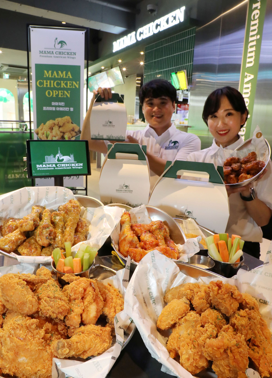 Staff show Mama Chicken's new chicken menu at its flagship store in Yonggang-dong, Mapo District, western Seoul. [PAPA JOHN'S KOREA]
