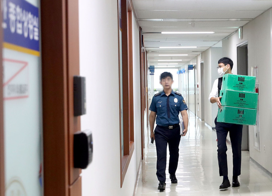 Right, an official with the prosecution’s probe team investigating the deadly underpass in Osong-eup of Cheongju, North Chungcheong, carries boxes into the Chungbuk Provincial Police in Cheongju on Monday during a raid to collect evidence. [YONHAP]