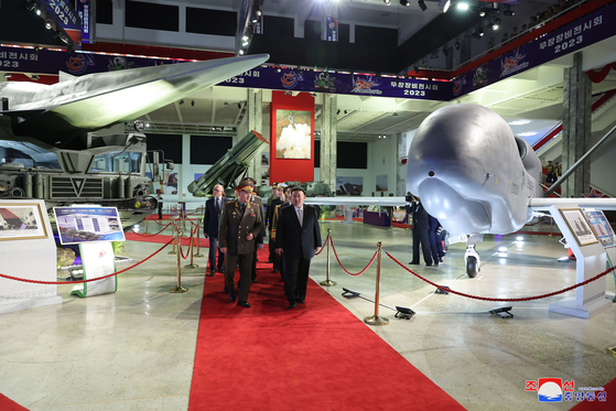 In this photo released by Pyongyang's state-controlled Korean Central News Agency, North Korean leader walks alongside Russian Defense Minister Sergei Shoigu at the Weaponry Exhibition-2023 in Pyongyang on Wednesday. A Hwasong-12 hypersonic guide vehicle is on the left side of the red carpet, while a new drone can be seen on the right. [YONHAP]