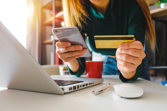 A person holds on to a credit card and a cell phone. [SHUTTERSTOCK]