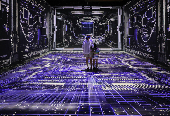 People at a media art exhibition titled ″Dear Earth : Time Walker″ held at Hyundai Department Store in Pangyo, Gyeonggi, on Sunday. The exhibition runs through Sept. 3. [YONHAP] 