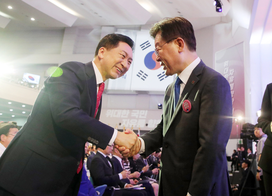 Kim Gi-hyeon, left, head of the People Power Party (PPP), and Lee Jae-myung, chief of the Democratic Party (DP), shake hands at a ceremony to mark Liberation Day at a Ewha Womans University auditorium in central Seoul Tuesday. [YONHAP] 