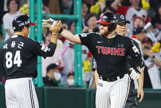 Austin Dean of the LG Twins, right, high fives third-base coach Park Yong-geun after hitting a two-run single and advancing to third on an error in the seventh inning of a game against the SSG Landers and Incheon SSG Landers Field in Incheon on Friday.  [YONHAP]