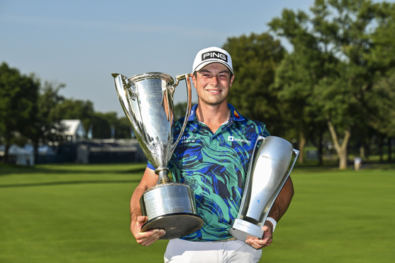 Viktor Hovland of Norway smiles with the Western Golf Association trophy, left, and the BMW Championship trophy after his victory in the final round of the BMW Championship, the second event of the FedExCup Playoffs, on the North Course at Olympia Fields Country Club in Olympia Fields, Illinois on Sunday. [GETTY IMAGES] 