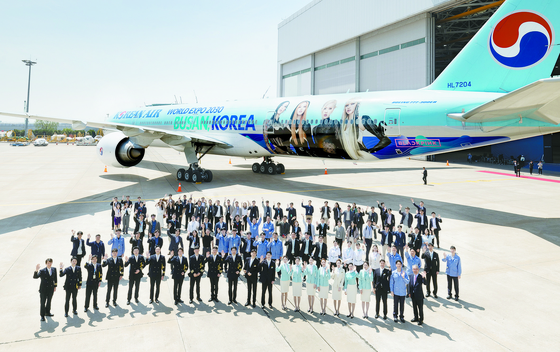 Korean Air cabin crew and staffs pose in front of its aircraft wrapped with Busan expo logo and K-pop girl group Black Pink. [KOREAN AIR]