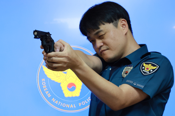 A police officer aims a gun that had been modified to be less lethal at the National Police Agency in Seoul on Tuesday. [YONHAP]