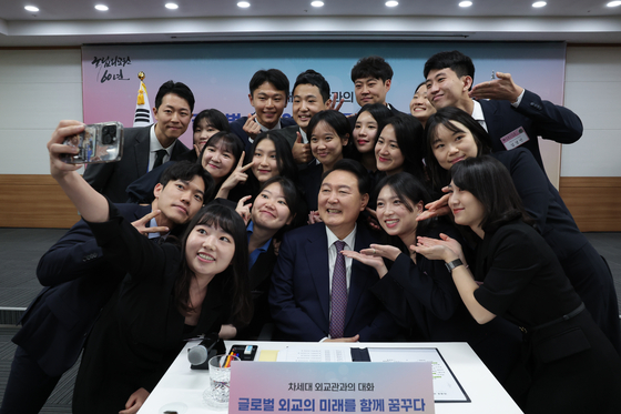 President Yoon Suk Yeol takes pictures with those that participated in the ceremony celebrating the 60th anniversary of the Korean National Diplomatic Academy in Seocho-dong, Seoul, on Friday. [YONHAP] 