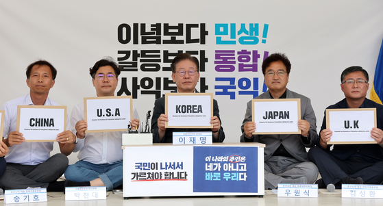 Lee Jae-myung, chairman of the Democratic Party, center, and other lawmakers show the covers of letters to be sent to President Yoon Suk Yeol and leaders of other countries that are parties to an international convention on maritime pollution to raise concerns over Japan's Fukushima water release in a press conference in front of the National Assembly in Yeouido, western Seoul, Sunday. [NEWS1]