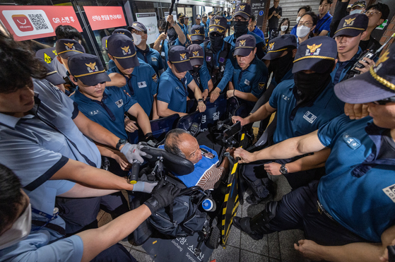  Members of Solidarity Against Disability Discrimination (SADD) scuffle with police while attempting to board the subway at Seoul City Hall Station, line No. 2 during a protest on Monday. Trains were delayed 10 to 15 minutes due to the altercation. SADD, which opposes the Seoul Metropolitan Government’s budget cut for next year, gathered for the first time in eight months on Sept. 5. SADD said it plans to hold protests at public transportation sites on Monday.. [NEWS1] 