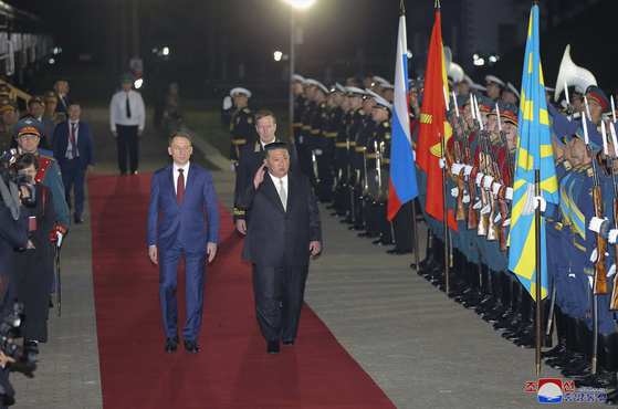 North Korean leader Kim Jong-un, right, salutes an honor guard in a welcome ceremony after crossing the border to Russia at Khasan Tuesday, where he was greeted by Russian Minister of Natural Resources and Ecology Alexander Kozlov, left, in a photo provided by the North’s Korean Central News Agency Wednesday. [YONHAP]