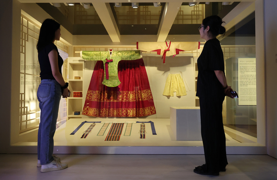 Visitors look at wedding gowns worn by women of the Joseon Dynasty at the National Palace Museum's ongoing exhibit, "Blooming Hwarot: Bridal Robes of the Joseon Royal Court." [YONHAP] 