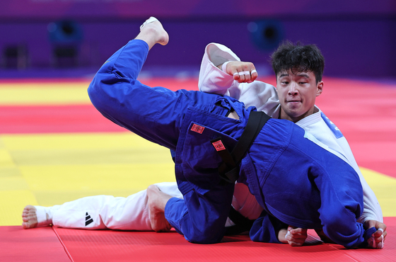 An Ba-ul, wearing blue, faces Japan's Ryoma Tanaka in the men's judo -66 kilograms division semifinal match in Hangzhou, China on Sunday. [YONHAP]
