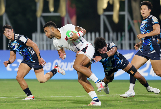 Korea's Kim Chan-ju tackles a Hong Kong player during the final of men's rugby sevens tournament at the Hangzhou Asian Games in Hangzhou, China on Tuesday.  [YONHAP]