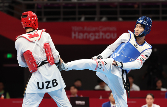 Korean taekwondo practitioner Jin Ho-jun, right, kicks Rashitov Ulugbek of Uzbekistan in the men’s -68kg semifinal at the Hangzhou Asian Games held at Lin'an Sports Culture Convention & Exhibition Center Gymnasium in Hangzhou, China on Wednesday. [YONHAP]