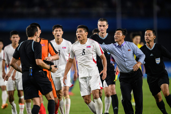 North Korea's Kim Kyong-sok, center, rounds on referee Rustam Lutfullin during a men's quarterfinal match between North Korea and Japan at the Hangzhou Asian Games in Hangzhou, China on Sunday.  [AFP/YONHAP]