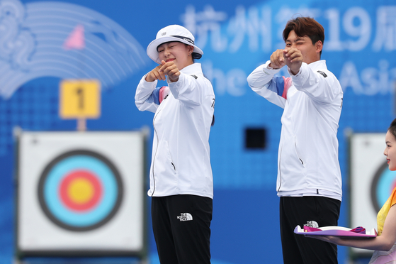 Korea's Lim Si-hyeon, left, and Lee Woo-seok celebrate on the podium after beating Japan in the final to take the mixed team recurve archery gold medal at the Hangzhou Asian Games in Hangzhou, China on Wednesday.  [NEWS1]