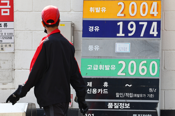 A passerby looks towards a signboard showing gas prices in Seoul on Wednesday. The average gasoline price nationwide rose for 12 consecutive weeks to reach 1,796.32 won ($1.32) per liter early morning Wednesday, according to Opinet, the Korea National Oil Corporation’s oil price management system. The price of diesel rose 0.11 won to 1,700.03 won. [YONHAP]