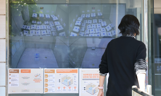 A pedestrian watches CCTV footage monitoring early voting ballot boxes for the Gangseo District office head shown around the clock at the entrance to the Seoul City Election Commission in Jongno District, central Seoul, Wednesday morning, the day of the by-election. Polling booths were open from 6 a.m. to 8 p.m. to all eligible voters on this day. [YONHAP]
