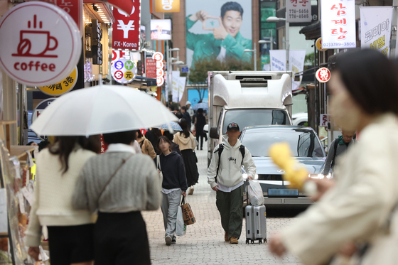 People stroll across a busy street in Myeong-dong, central Seoul on Monday. While Chinese group tours in Korea have resumed in August, the number of Chinese group tourists have dwindled, with more individual tourists, especially from the MZ generation, visiting Korea instead. [YONHAP]