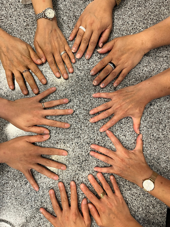 Korea-born adoptees adopted in Korea and overseas put their hands together on a cafe table where they met to hear more from a birth mother and share their experiences in Seoul on July 21. [ESTHER CHUNG]
