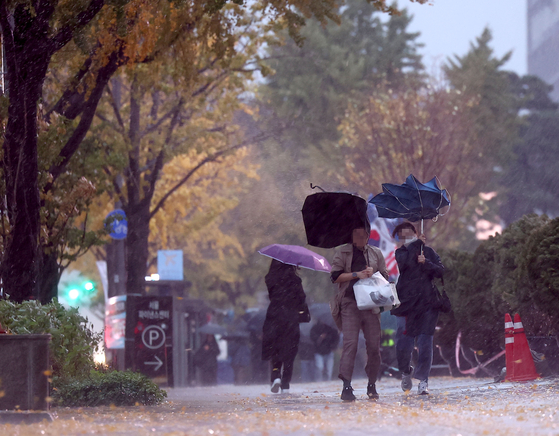 People walk through strong winds in downtown Seoul on Monday. [YONHAP] 