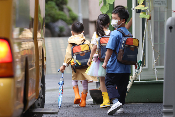 Children get ready to ride the school bus heading to their kindergarten on Aug. 1 in 2022 in Seoul. [YONHAP]