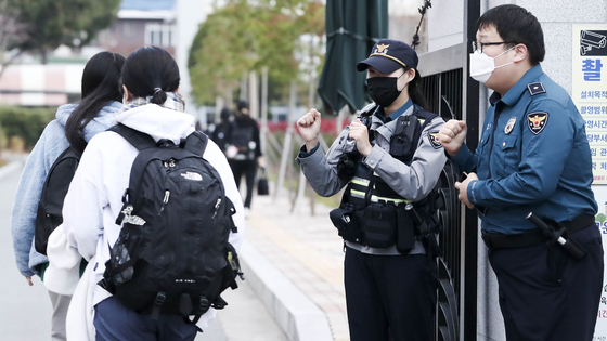 Two police officers encourage test-takers arriving at their test site, Ulsan Girl's High School in Nam District, Ulsan on Nov. 17, 2022. [NEWS1]