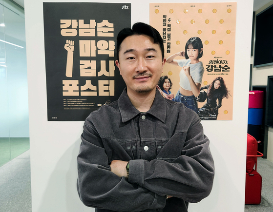 Kim Kang-min, the art director behind the promotional posters for the drama series ″Strong Girl Nam-soon,″ poses for a photo with the posters in the background. Stickers on the poster contain drug reagents that can be used to test beverages for drugs. [CHEIL WORLDWIDE]
