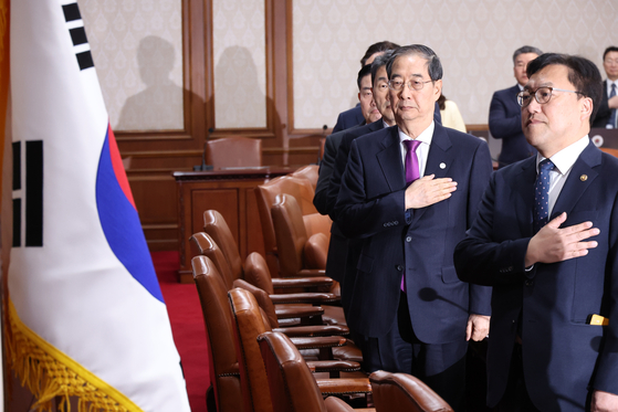 Prime Minister Han Duck-soo and Cabinet members salute to the Korean flag at the Cabinet meeting held on Wednesday morning at governmental complex in central Seoul. [YONHAP] 