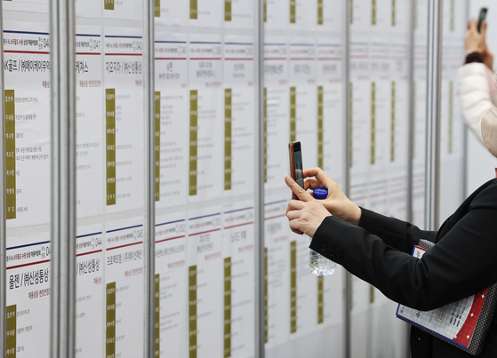 A job seeker takes photos of recruitment posters at job fair held in Suwon, Gyeonggi in October. [YONHAP]